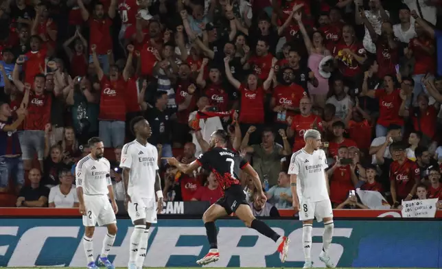 Mallorca's Vedat Muriqi, centre, runs past Real Madrid's Dani Carvajal, left, Vinicius Junior, 2nd left and Federico Valverde, right, while celebrating after scoring his side's first goal during a Spanish La Liga soccer match between Mallorca and Real Madrid at the Son Moix Stadium in Palma de Mallorca, Spain, Sunday, Aug. 18, 2024. (AP Photo/Francisco Ubilla)