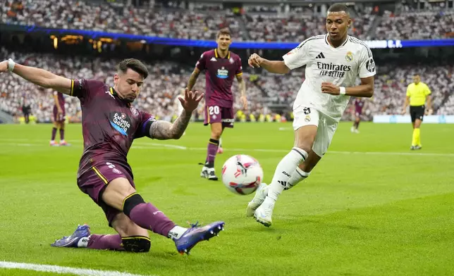 Real Madrid's Kylian Mbappe, right, and Valladolid's Luis Perez challenge for the ball during the Spanish La Liga soccer match between Real Madrid and Valladolid at the Santiago Bernabeu stadium in Madrid, Spain, Sunday, Aug. 25, 2024. (AP Photo/Manu Fernandez)