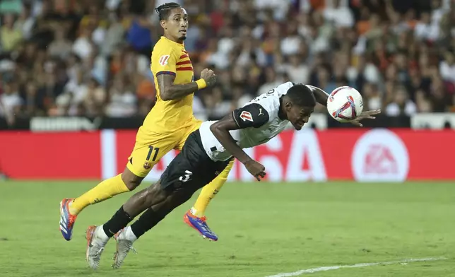 Valencia's Cristhian Mosquera, centre, heads the ball as Barcelona's Raphinha challenges during the Spanish La Liga soccer match between Valencia and FC Barcelona at the Mestalla stadium in Valencia, Spain, Saturday, Aug. 17, 2024. (AP Photo/Alberto Saiz)