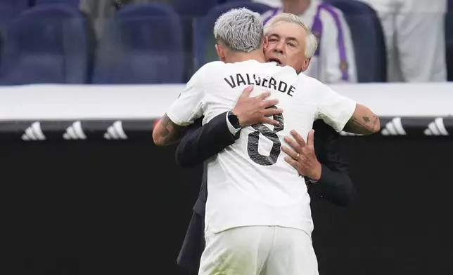 Real Madrid's Federico Valverde, back to the camera, celebrates with Real Madrid's head coach Carlo Ancelotti after scoring the opening goal during the Spanish La Liga soccer match between Real Madrid and Valladolid at the Santiago Bernabeu stadium in Madrid, Spain, Sunday, Aug. 25, 2024. (AP Photo/Manu Fernandez)