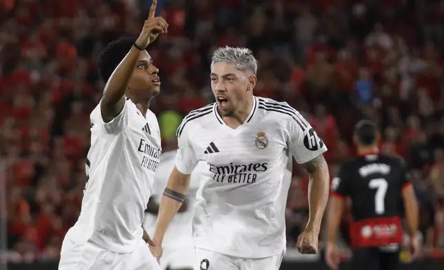 Real Madrid's Rodrygo, left, celebrates with Federico Valverde after scoring the opening goal during a Spanish La Liga soccer match between Mallorca and Real Madrid at the Son Moix Stadium in Palma de Mallorca, Spain, Sunday, Aug. 18, 2024. (AP Photo/Francisco Ubilla)