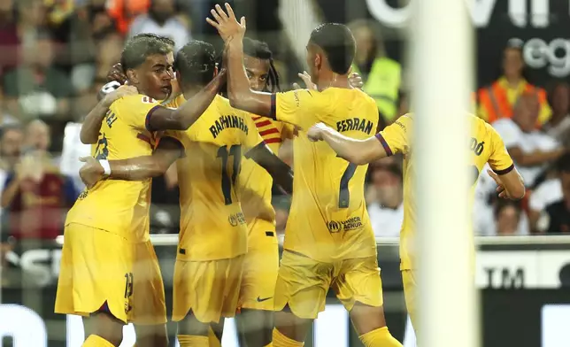 Barcelona's team players celebrate after Robert Lewandowski scored his side's first goal during the Spanish La Liga soccer match between Valencia and FC Barcelona at the Mestalla stadium in Valencia, Spain, Saturday, Aug. 17, 2024. (AP Photo/Alberto Saiz)