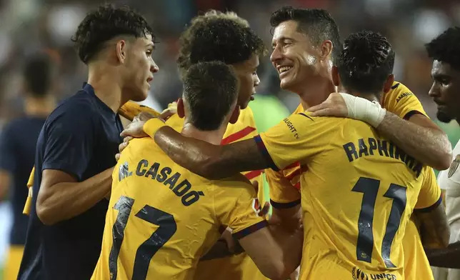 Valencia's Thierry Correia, right, walks as Barcelona's team players celebrate after the Spanish La Liga soccer match between Valencia and FC Barcelona at the Mestalla stadium in Valencia, Spain, Saturday, Aug. 17, 2024. (AP Photo/Alberto Saiz)