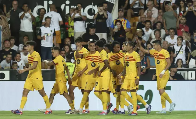 Barcelona's Robert Lewandowski, right, celebrates with teammates after scoring his side's second goal during the Spanish La Liga soccer match between Valencia and FC Barcelona at the Mestalla stadium in Valencia, Spain, Saturday, Aug. 17, 2024. (AP Photo/Alberto Saiz)