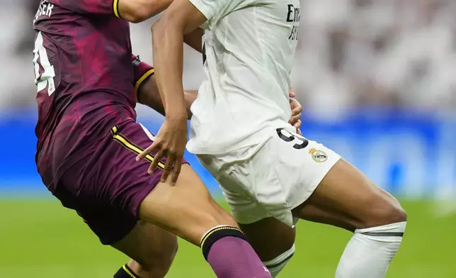 Real Madrid's Kylian Mbappe, right, and Valladolid's Victor Meseguer challenge for the ball during the Spanish La Liga soccer match between Real Madrid and Valladolid at the Santiago Bernabeu stadium in Madrid, Spain, Sunday, Aug. 25, 2024. (AP Photo/Manu Fernandez)