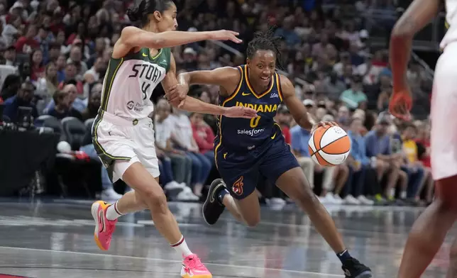 Indiana Fever's Kelsey Mitchell (0) goes to th basket against Seattle Storm's Skylar Diggins-Smith (4) during the first half of a WNBA basketball game, Sunday, Aug. 18, 2024, in Indianapolis. (AP Photo/Darron Cummings)