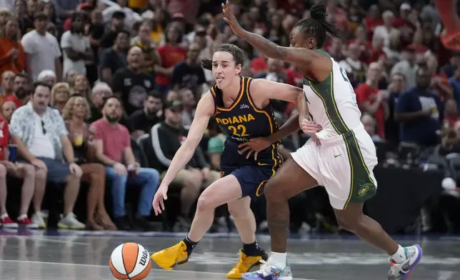 Indiana Fever's Caitlin Clark (22) goes to the basket against Seattle Storm's Jewell Loyd, right, during the first half of a WNBA basketball game, Sunday, Aug. 18, 2024, in Indianapolis. (AP Photo/Darron Cummings)