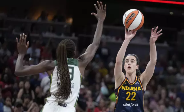 Indiana Fever's Caitlin Clark (22) shoots over Seattle Storm's Ezi Magbegor, left, during the first half of a WNBA basketball game, Sunday, Aug. 18, 2024, in Indianapolis. (AP Photo/Darron Cummings)