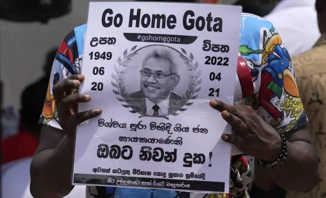 FILE -A protestor holds a poster designed as a death notification of Sri Lankan President Gotabaya Rajapaksa at the ongoing protest site outside the president's office in Colombo, Sri Lanka, Thursday, April 21, 2022. (AP Photo/Eranga Jayawardena, File)