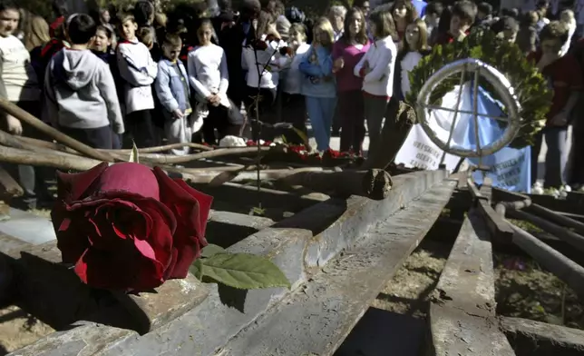 FILE -Students stand behind the wreckage of a gate at Athens Polytechnic, that was the center of an uprising in 1973 against the military dictatorship then ruling Greece, Nov. 16, 2006. (AP Photo/Petros Giannakouris, File)