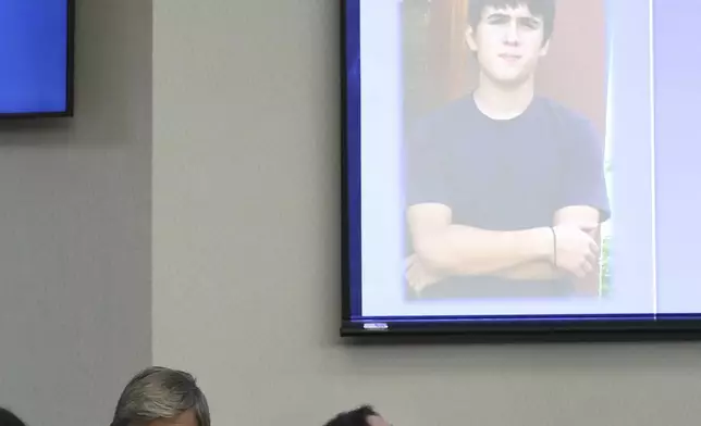 Rose Marie Kosmetatos looks up at a photo of her son, accused Santa Fe High School shooter Dimitrios Pagourtzis, as she and her husband, Antonios Pagourtzis, listen to opening statements in the civil trial against them in Galveston County Court No. 3 Judge Jack Ewing's courtroom at the Galveston County Courthouse in Galveston, Texas on Wednesday, July 31, 2024. (Jennifer Reynolds/The Galveston County Daily News via AP, Pool)