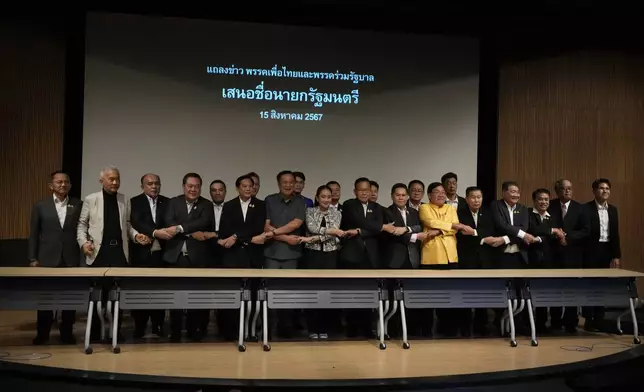 Leader of Pheu Thai Party, Paetongtarn Shinawatra, daughter of Thailand's former Prime Minister Thaksin Shinawatra, eight form left, and coalition partners shake hand during press conference in Bangkok, Thailand, Thursday, Aug. 15, 2024. (AP Photo/Sakchai Lalit)