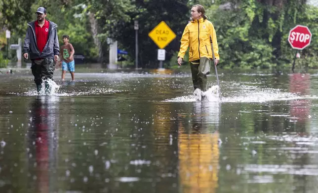 Rebecca Fanning, right, who works for the town of Sullivan's Island, inspects flood waters as Charles Drayton, also an employee of Sullivan's Island and his son McKain, 8, walk behind on Atlantic Ave. as Tropical Storm Debby approaches, Wednesday, Aug. 7, 2024, in Sullivan's Island, S.C. (AP Photo/Mic Smith)