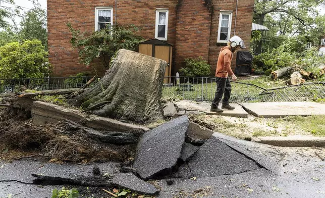 A tree service worker walks past an uprooted tree on Adrian Street in Harrisburg, Pa., after extreme weather from Tropical storm Debby, Friday, Aug. 9, 2024. (Sean Simmers/The Patriot-News via AP)