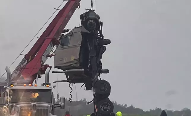 The cab of a tractor trailer is raised from a bridge on Interstate 75 near Tampa, Fla., early Monday, Aug. 5, 2024, after the truck collided with a concrete wall, flipped over the wall, and was left dangling from the bridge. The driver was killed. The truck’s cab broke off and dropped into the Tampa Bypass Canal. Sheriff’s office divers located the 64-year-old man from New Albany, Mississippi in the cab 40 feet below the surface, according to the Florida Highway Patrol. (Florida Highway Patrol via AP)