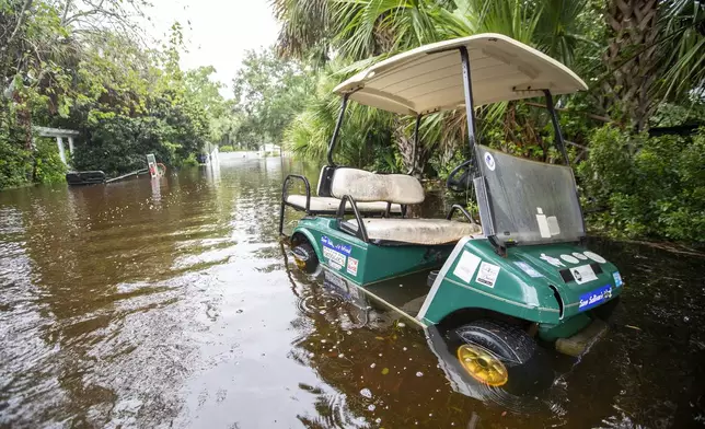 A golf cart sits in flood waters on Atlantic Ave. as Tropical Storm Debby approaches, Wednesday, Aug. 7, 2024, in Sullivan's Island, S.C. (AP Photo/Mic Smith)