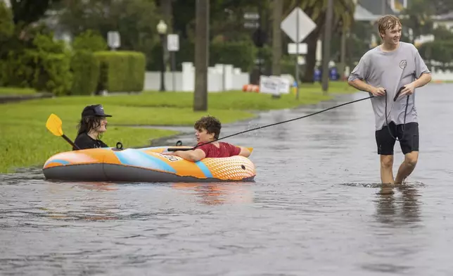 Landon Stanley pulls his friends Jakob Jackson and Emerson Porcelli-Wilson in the waters flooding the streets from Tropical Storm Debby on Sunday, Aug. 4, 2024 in Tampa, Fla. (Luis Santana/Tampa Bay Times via AP)