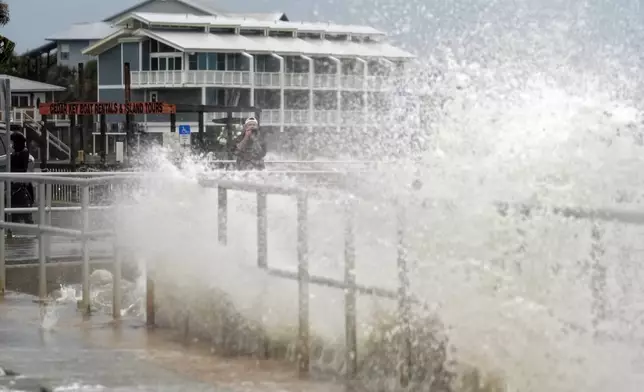 A man takes photos of the surf pushed by winds from Tropical Storm Debby as they break over the sea wall in Cedar Key, Fla., on Sunday, Aug. 4, 2024. (AP Photo/Christopher O'Meara)