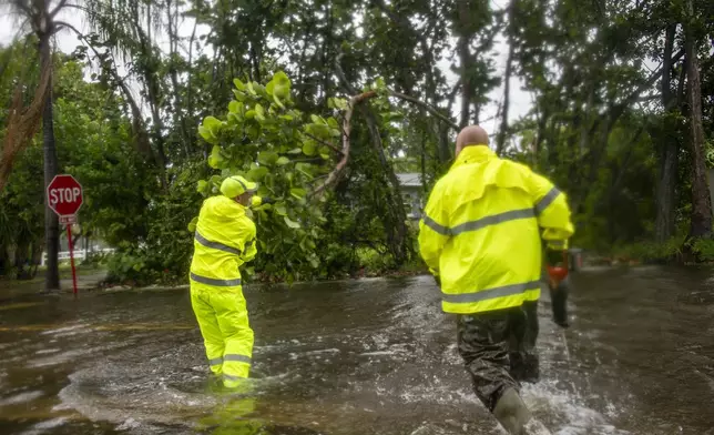 St. Petersburg Stormwater Management workers Mariano Morales, left, and Brad Sharp, work to clear debris from a flooded street in Shore Acres during Tropical Storm Debby Sunday afternoon, Aug. 4, 2024. (Dylan Townsend/Tampa Bay Times via AP)