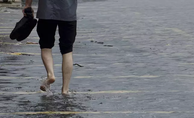 A man walks to work in the flooded streets of downtown Baltimore on Friday, Aug. 9, 2024 (Kaitlin Newman/The Baltimore Banner via AP)