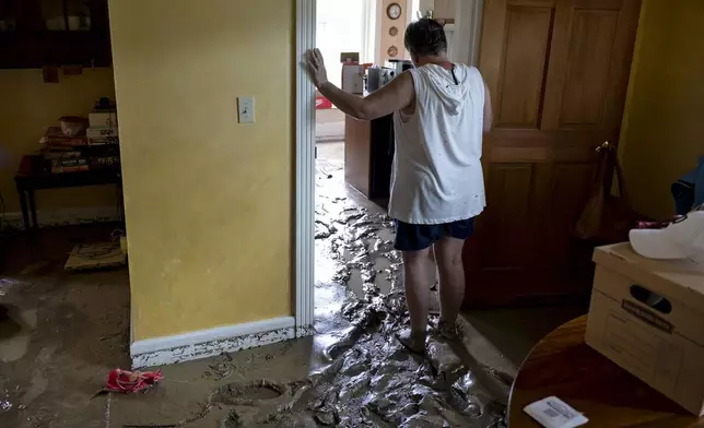 Ann Farkas walks in her flood-damaged home in Canisteo, N.Y., Friday, Aug. 9, 2024, after remnants of Tropical Storm Debby swept tough the area, creating flash flood conditions in some areas. (AP Photo/Craig Ruttle)