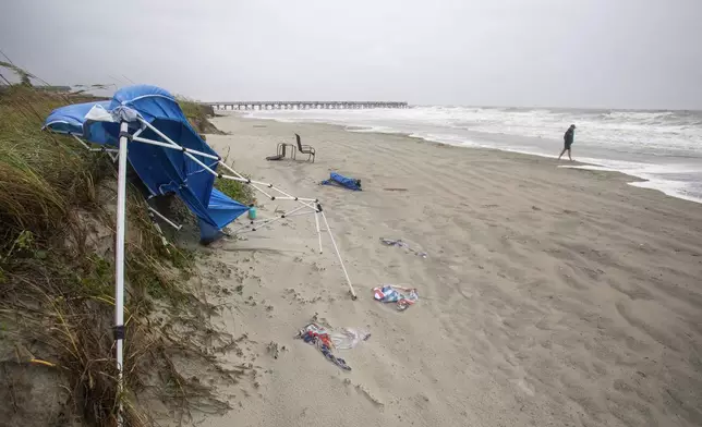 A person walks on a windy and rainy beach as Tropical Storm Debby approaches the area, Tuesday, Aug. 6, 2024, in Isle of Palms, S.C. (AP Photo/Mic Smith)