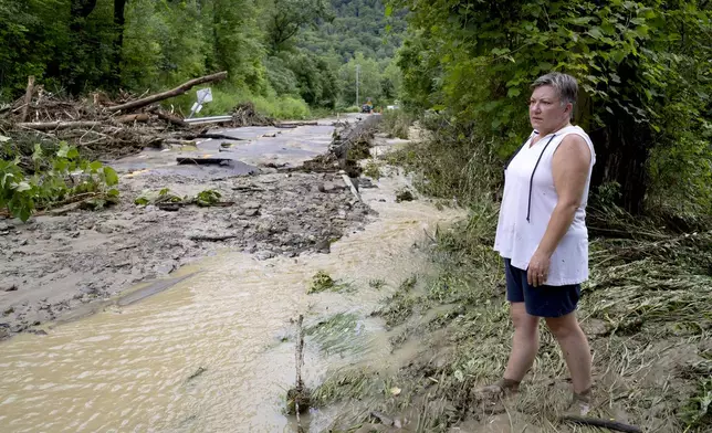 Ann Farkas stands near the waterway that flooded her home in Canisteo, N.Y. Friday, Aug. 9, 2024, after remnants of Tropical Storm Debby swept tough the area, creating flash flood conditions in some areas. (AP Photo/Craig Ruttle)