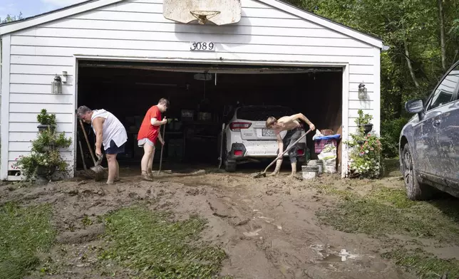 Ann Farkas, left, works with her daughter Alex Farkas and family friend Damian Hartman as they clean up the Farkas home in Canisteo, N.Y., Friday, Aug. 9, 2024, after remnants of Tropical Storm Debby swept tough the area, creating flash flood conditions in some areas. (AP Photo/Craig Ruttle)