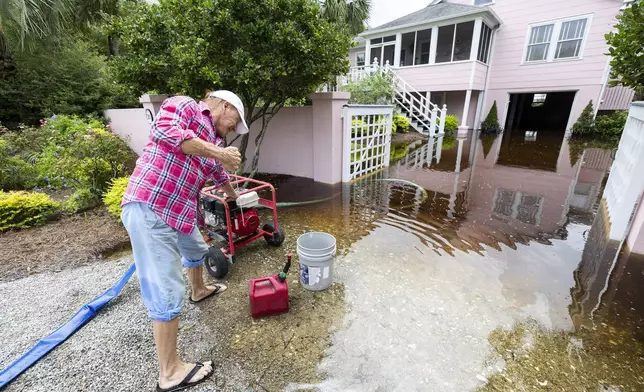 Robert Chesnut starts his water pump at his Palm Blvd. home after it was flooded by Tropical Storm Debby Thursday, Aug. 8, 2024, in Isle of Palms, S.C. (AP Photo/Mic Smith)