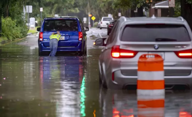 The driver of a stranded vehicle pushes his van out of a flooded street after heavy rain from Tropical Storm Debby, Monday, Aug. 5, 2024, in Savannah, Ga. (AP Photo/Stephen B. Morton)