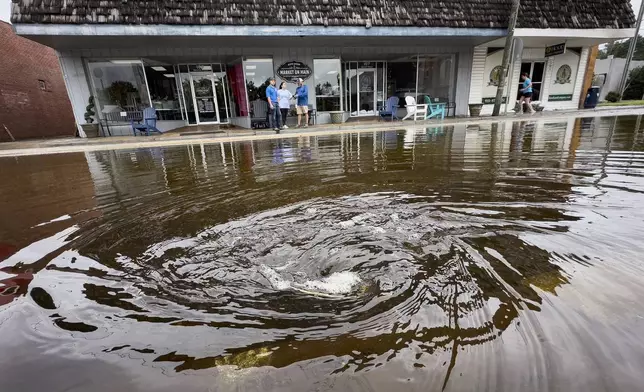 A drain pulls in residual rain water floods the downtown area caused by Tropical Storm Debby, Thursday, Aug. 8, 2024, in Bladenboro, NC. (AP Photo/John Minchillo)