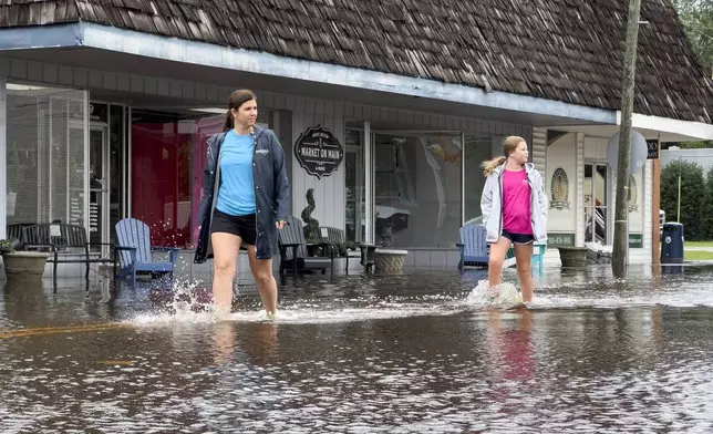 Emily Peterson Dowless, left, walks past her business Market on Main as residual rain water floods the downtown area caused by Tropical Storm Debby, Thursday, Aug. 8, 2024, in Bladenboro, NC. (AP Photo/John Minchillo)