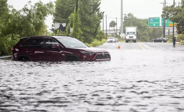 A car sits in flood waters near Spruill Ave in North Charleston, S.C., as Tropical Storm Debby approaches, Tuesday, Aug. 6, 2024. (AP Photo/Mic Smith)