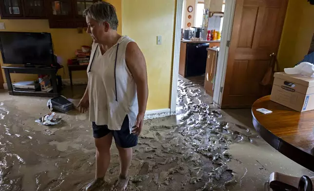 Ann Farkas walks in her flood-damaged home in Canisteo, N.Y., Friday, Aug. 9, 2024, after remnants of Tropical Storm Debby swept tough the area, creating flash flood conditions in some areas. (AP Photo/Craig Ruttle)