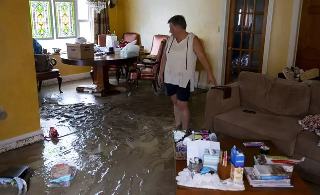 Ann Farkas walks in her flood-damaged home in Canisteo, N.Y., Friday, Aug. 9, 2024, after remnants of Tropical Storm Debby swept through the area, creating flash flood conditions in some areas. (AP Photo/Craig Ruttle)