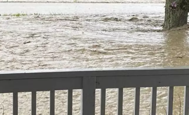 This photo provided by Deb Moss shows massive flooding at a farm in Canisteo, N.Y., as a double-wide trailer is seen floating downriver in the distance, Friday, Aug. 9, 2024. (Deb Moss via AP)