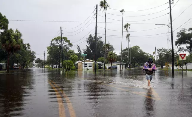 Carter Grooms, 25, of Tampa, wades through the streets in the Shore Acres neighborhood of St. Petersburg, Fla., Monday morning, Aug 5, 2024, as Hurricane Debby passed the Tampa Bay area offshore. (Dylan Townsend/Tampa Bay Times via AP)