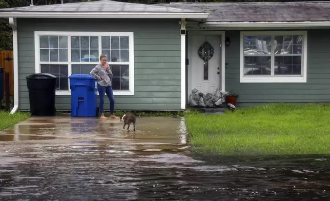 Kim Paul, 60, and her dog, Diesel, in front of their Shore Acres residence, as floodwaters reaches nearly halfway up her driveway, Monday morning, Aug 5, 2024, as Hurricane Debby passed the Tampa Bay area offshore. (Dylan Townsend/Tampa Bay Times via AP)