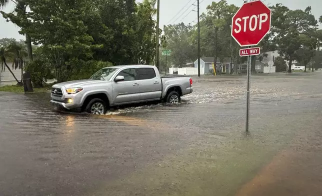 A driver negotiates a flooded street in the Shore Acres area Monday morning, Aug. 5, 2024, St. Petersburg, Fla., as Hurricane Debby passes the Tampa Bay area offshore. (Max Chesnes/Tampa Bay Times via AP)