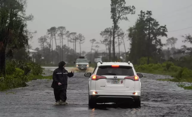 A man walks through storm surge on the flooded road into Horseshoe Beach, Fla., Monday morning, Aug. 5, 2024. Hurricane Debby made landfall early this morning. (AP Photo/Christopher O'Meara)