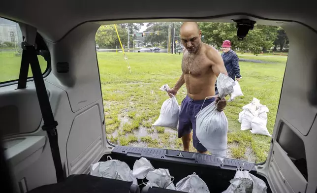 Savannah resident Roi Roizaken loads sandbags into his van as rain from Hurricane Debby starts to fall, Monday, Aug. 5, 2024, in Savannah, Ga. Forecasters warned heavy rain could spawn catastrophic flooding in Florida, South Carolina and Georgia. (AP Photo/Stephen B. Morton)