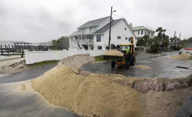 Tybee Island Department of Public Works employee Bruce Saunders uses a backhoe to pile sand as a barriers against storm surge from Tropical Storm Debby at a beach access point, Monday, Aug. 5, 2024, in Tybee Island, Ga. (AP Photo/Stephen B. Morton)