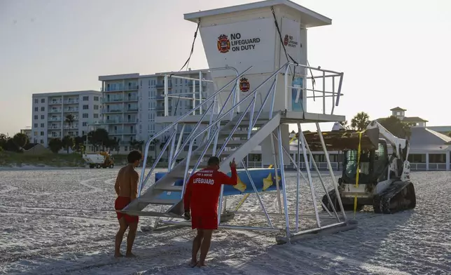 From left, Matthew Blowers and Patrick Brafford prepare to secure a lifeguard tower in preparation of potential storm at Clearwater Beach on Saturday, Aug. 3, 2024, in Clearwater, Fla. (Jefferee Woo/Tampa Bay Times via AP)