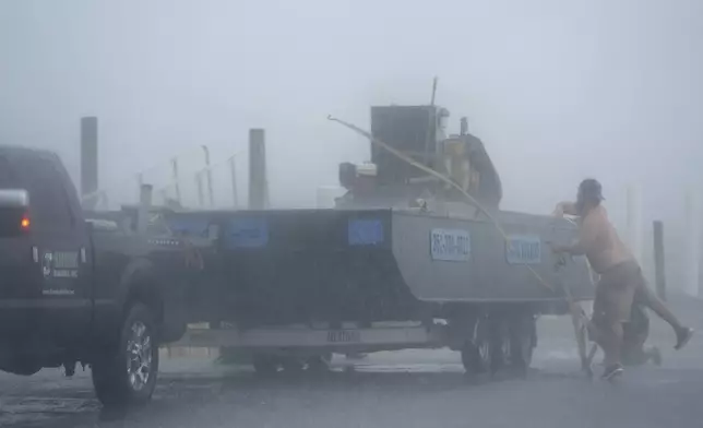 A man struggles to secure construction equipment against of the surf, pushed by winds from Tropical Storm Debby, in Cedar Key, Fla., on Sunday, Aug. 4, 2024. (AP Photo/Christopher O'Meara)