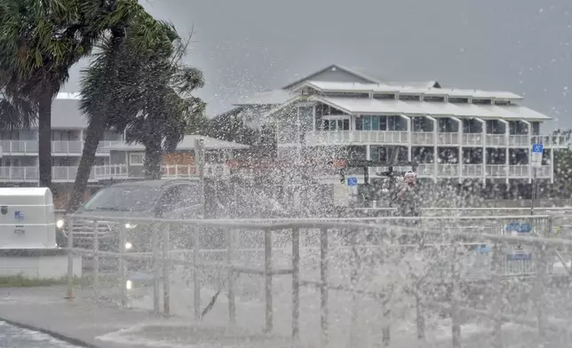 A man takes photos of the surf, pushed by winds from Tropical Storm Debby, break over the sea wall in Cedar Key, Fla., on Sunday, Aug. 4, 2024. (AP Photo/Christopher O'Meara)