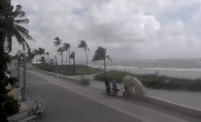 People walk along a windy Hollywood Beach as Tropical Storm Debby moves through the Gulf of Mexico toward Florida on Sunday, Aug. 4, 2024 in Hollywood, Fla. (WPLG via AP)