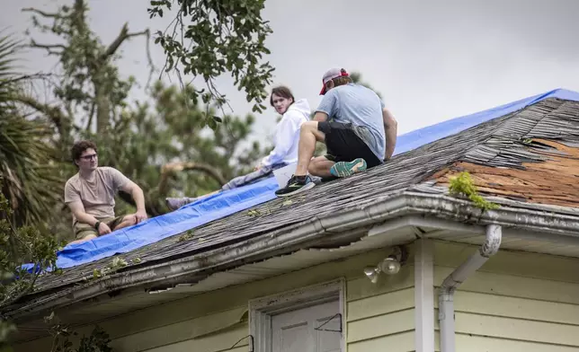 Residents repair their roof as high winds from an outer band from Tropical Storm Debby passed over the Isle of Palms, S.C., Tuesday, Aug. 6, 2024. (AP Photo/Mic Smith)