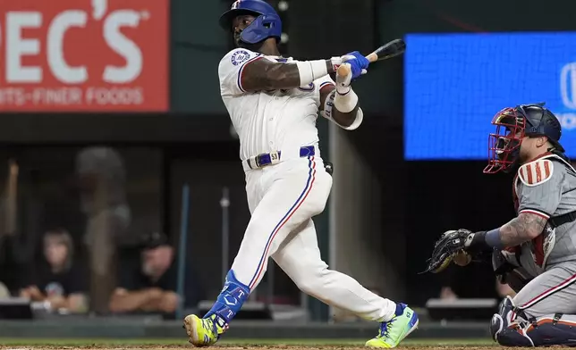 Texas Rangers right fielder Adolis Garcia follows through on a single as Minnesota Twins catcher Christian Vazquez, right, looks on in the fifth inning of a baseball game, Thursday, Aug. 15, 2024, in Arlington, Texas. (AP Photo/Tony Gutierrez)