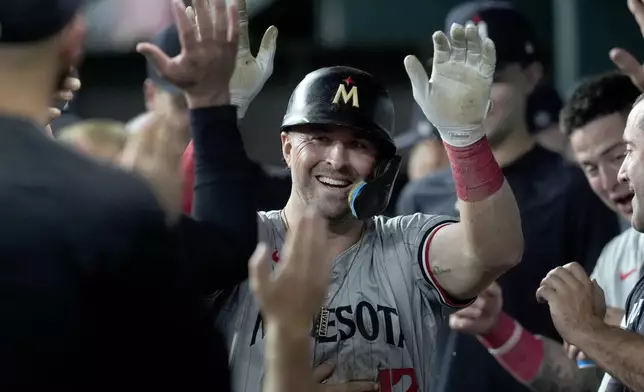 Minnesota Twins' Kyle Farmer (12) celebrates in the dugout after hitting a triple and then scoring on a fielding error by Texas Rangers' Leody Taveras in the second inning of a baseball game, Thursday, Aug. 15, 2024, in Arlington, Texas. (AP Photo/Tony Gutierrez)