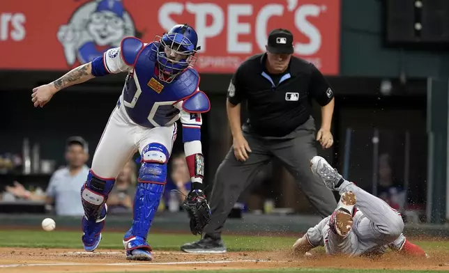 Texas Rangers' Jonah Heim reaches out for the throw to the plate as Minnesota Twins' Kyle Farmer scores after hitting a triple, then scoring on a fielding error by center fielder Leody Taveras, in the second inning of a baseball game, Thursday, Aug. 15, 2024, in Arlington, Texas. (AP Photo/Tony Gutierrez)